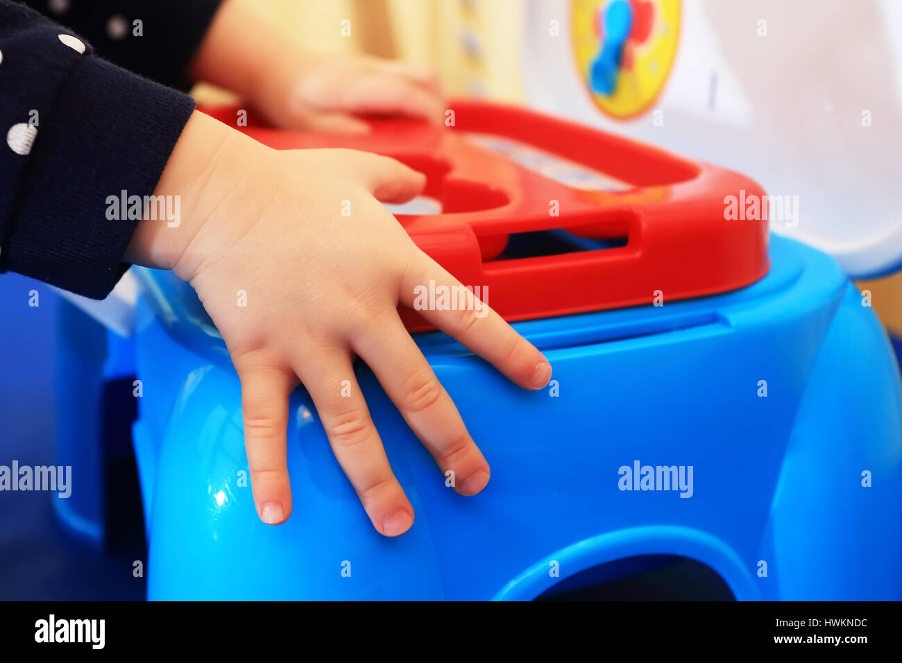 Les mains de l'enfant on colorful toy box close-up. Kid se replie les jouets dans la boîte bleue. Enfant lumineux arrière-plan. Banque D'Images