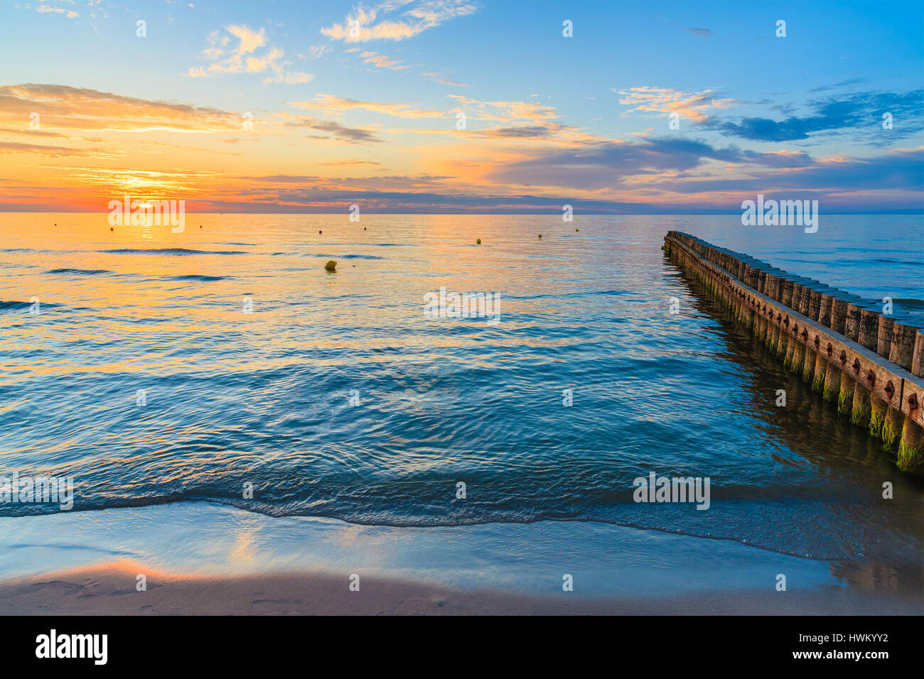 Coucher de soleil sur la mer avec des brise-lames en bois en avant-plan sur la plage de la mer Baltique, Leba, Pologne Banque D'Images