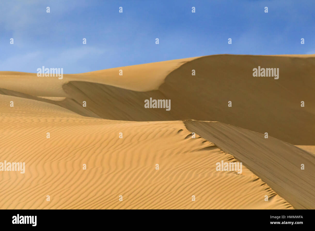 Fragment de texture minimaliste de dunes de sable jaune sous ciel bleu sur une journée ensoleillée. Paysage de désert, comme l'Australie. Banque D'Images