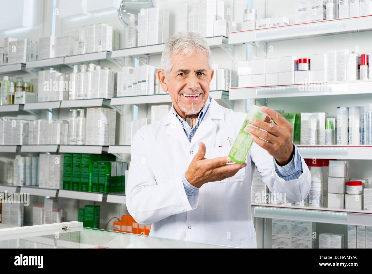 Confiant Pharmacist Smiling en maintenant le produit en pharmacie Banque D'Images