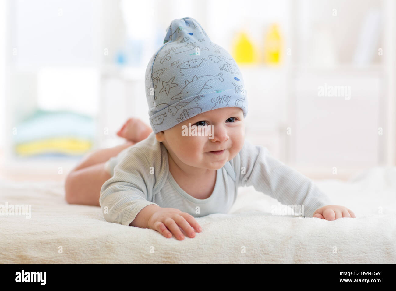 Bébé garçon allongé sur un tapis pour enfants à capuchon bleu. Banque D'Images