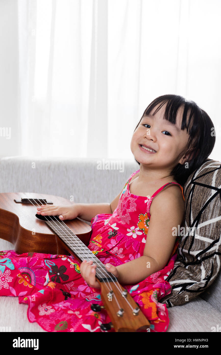 Chinois asiatique petite fille assise sur le canapé à l'ukele Banque D'Images