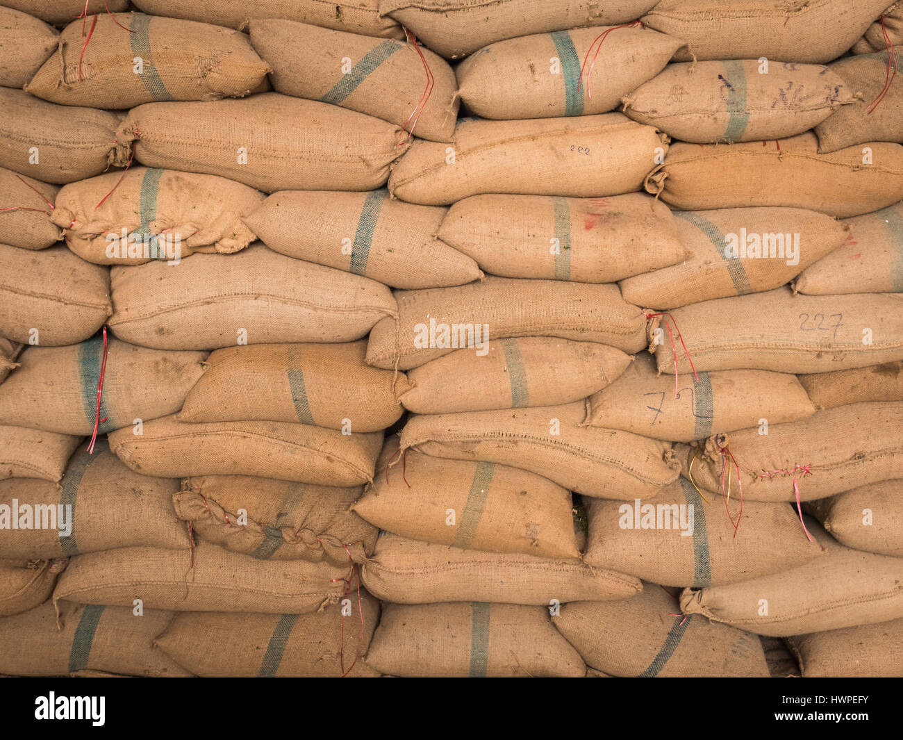 Vieux sacs de chanvre contenant du riz mis empilés dans une rangée. Banque D'Images