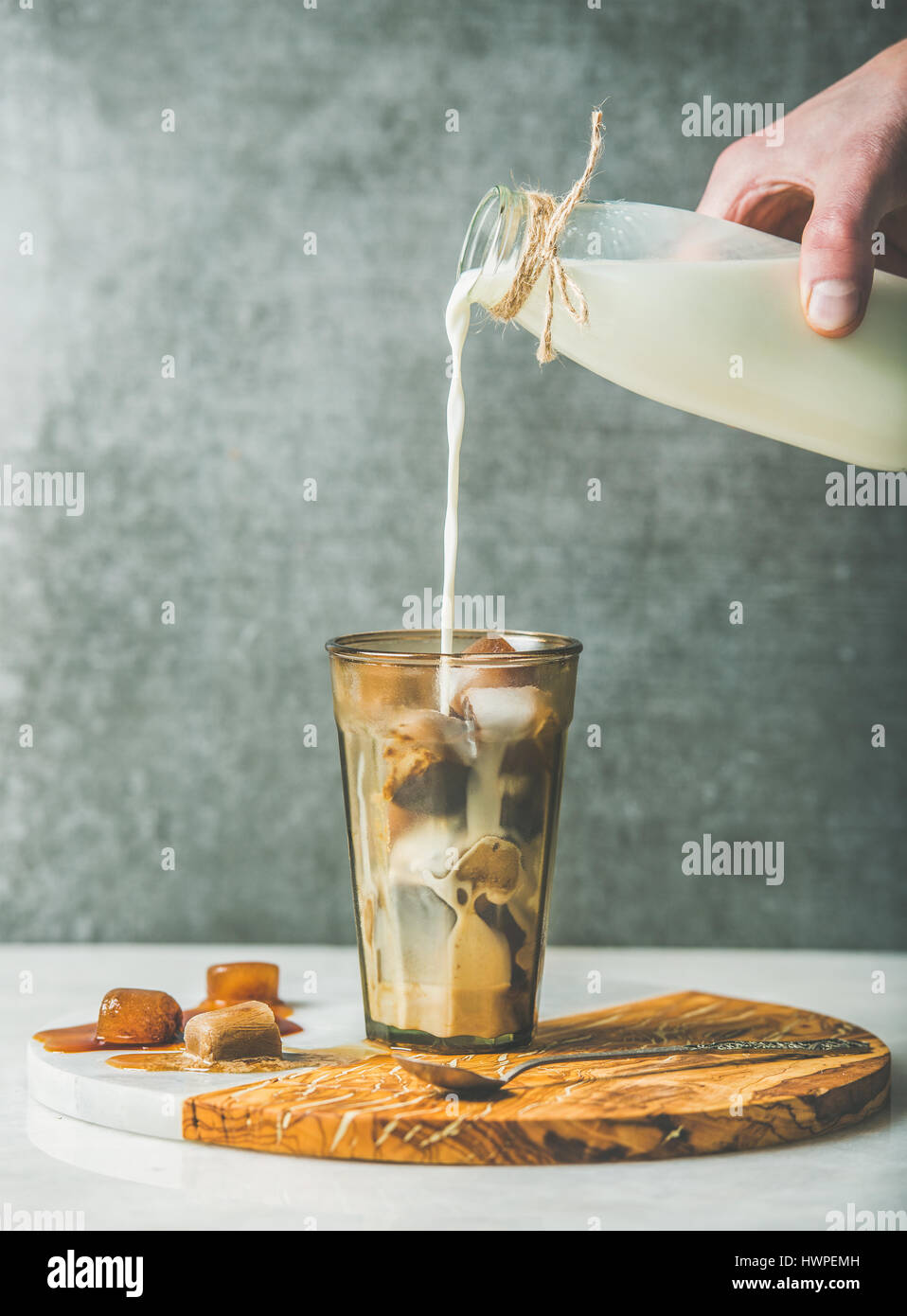 La main de l'homme de verser le lait de la bouteille au verre avec du café Banque D'Images