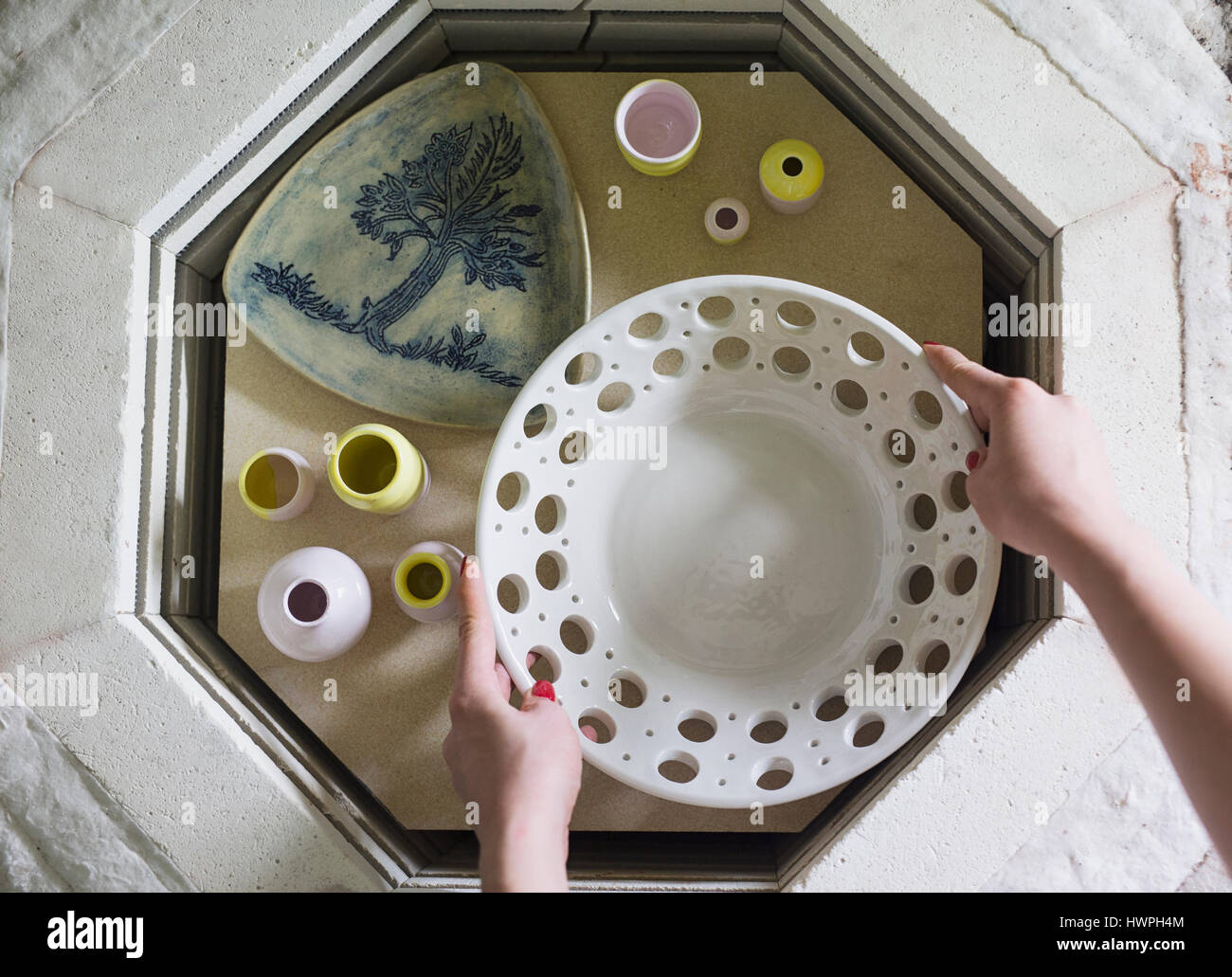 Vue de dessus de femme potter holding Bol en céramique à table dans l'atelier Banque D'Images