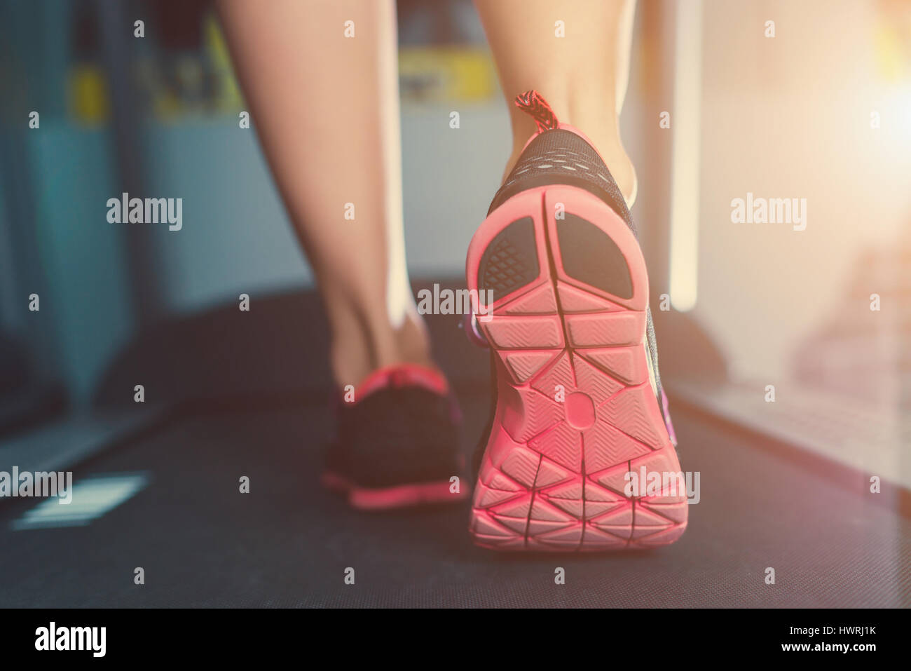 La femelle les pieds dans des chaussures d'exécution sur le tapis roulant à la salle de sport Banque D'Images