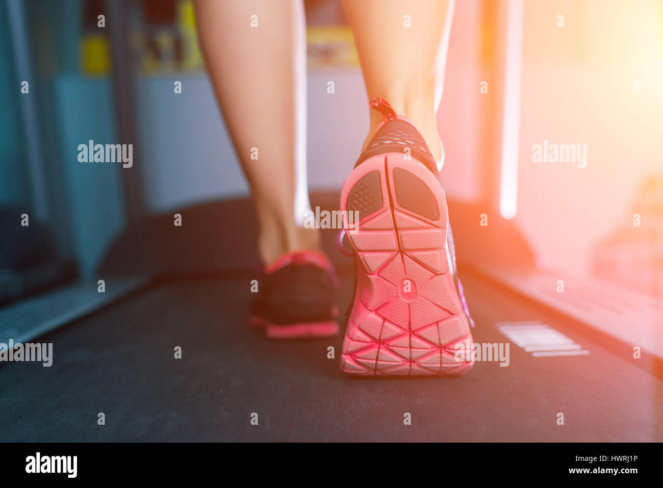 La femelle les pieds dans des chaussures d'exécution sur le tapis roulant à la salle de sport Banque D'Images