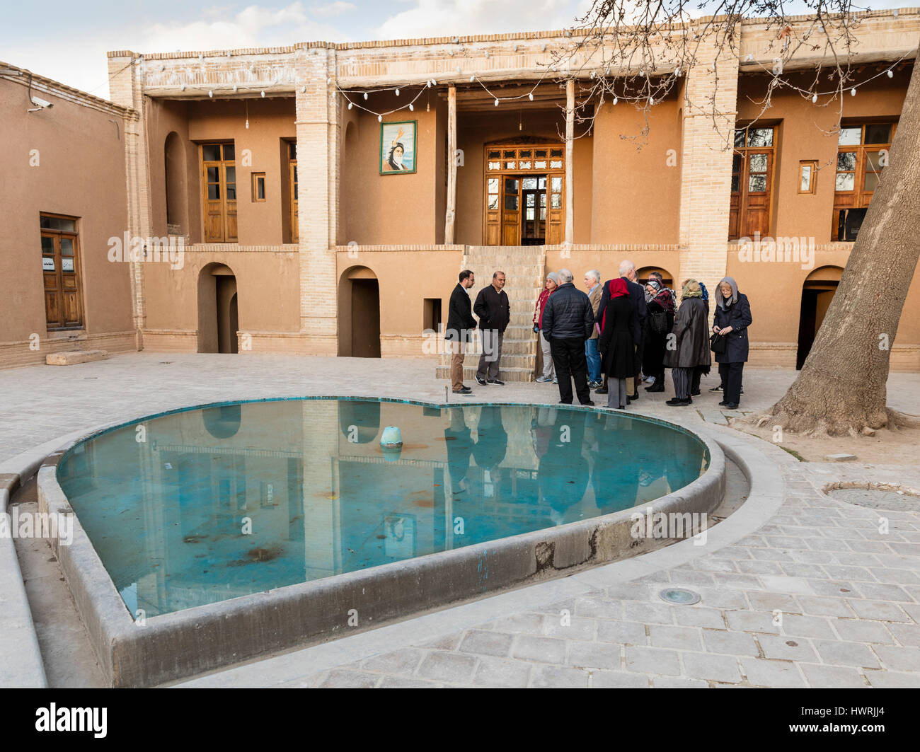 Habillé modestement les touristes américains avec guide visite de la maison natale de l'Ayatollah Khomeiny dans Khomeyn. Une fontaine en forme de coeur dans la cour avant-plan Banque D'Images