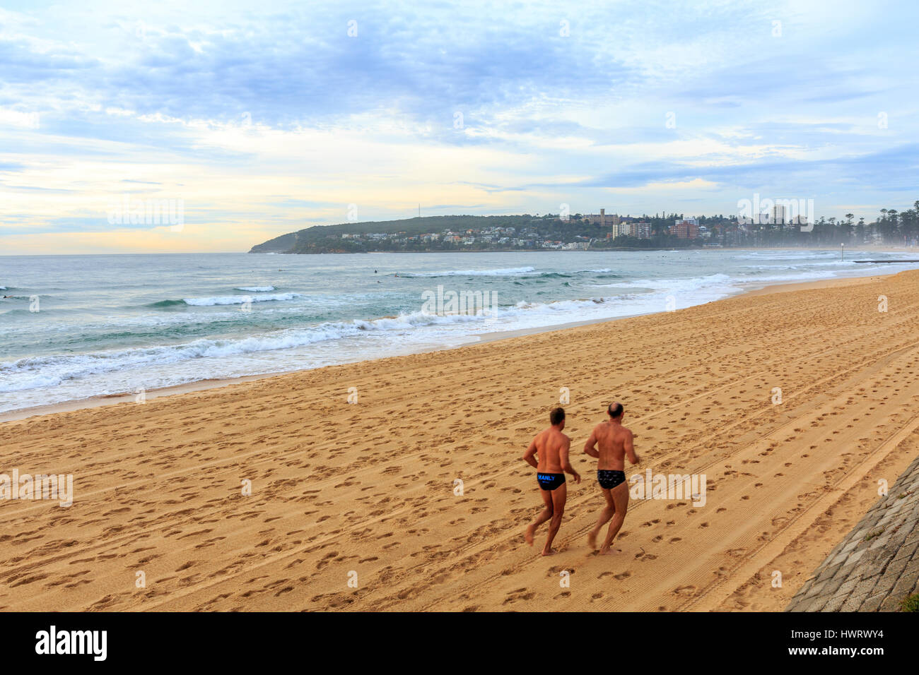 Personnes deux hommes s'exerçant en courant et en jogging sur Manly Beach à Dawn , Sydney, Australie Banque D'Images