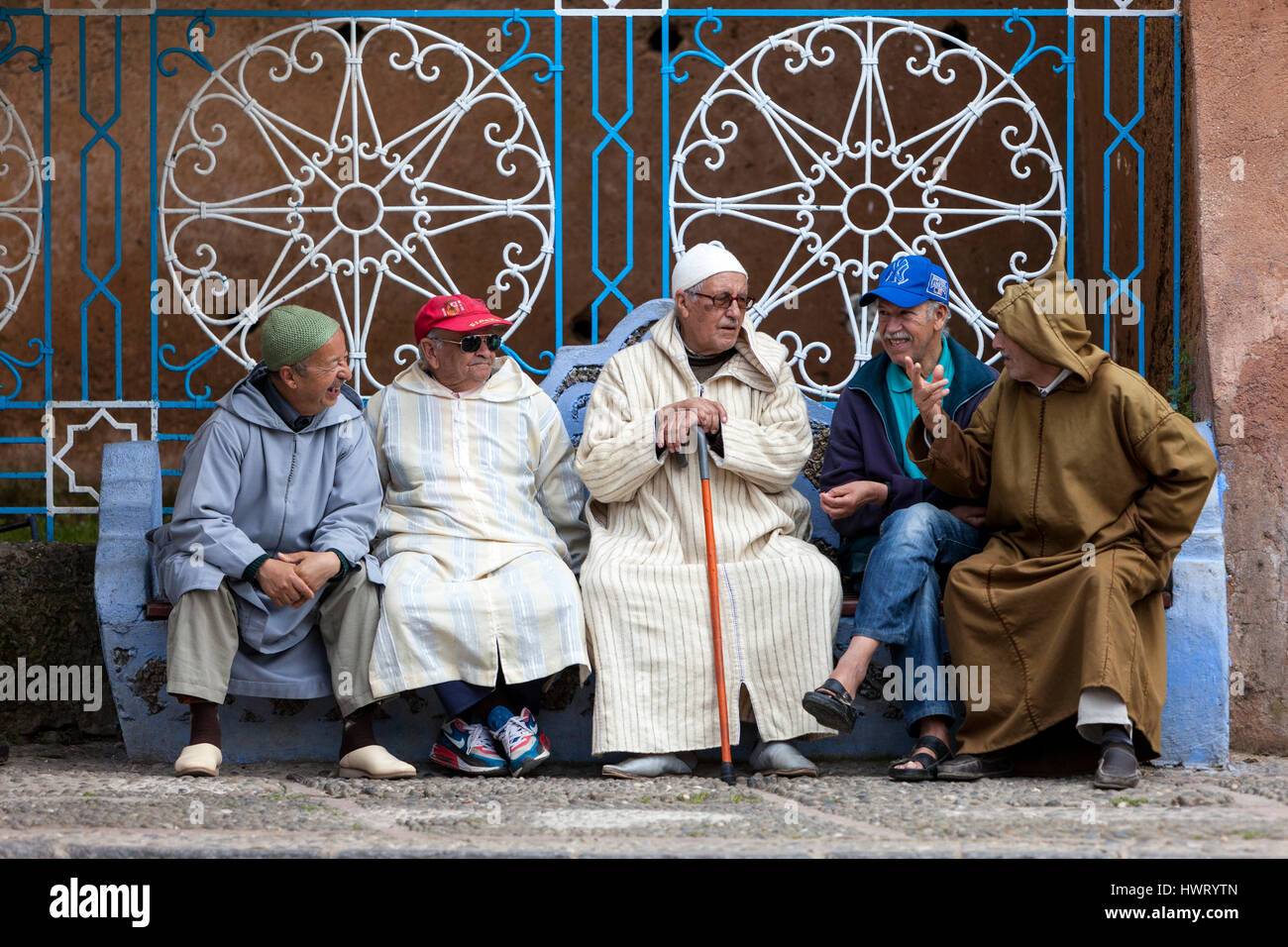 Chefchaouen, Maroc. Hommes parler sur la place publique, la démonstration d'une variété de styles de vêtements traditionnels et occidentaux. Banque D'Images