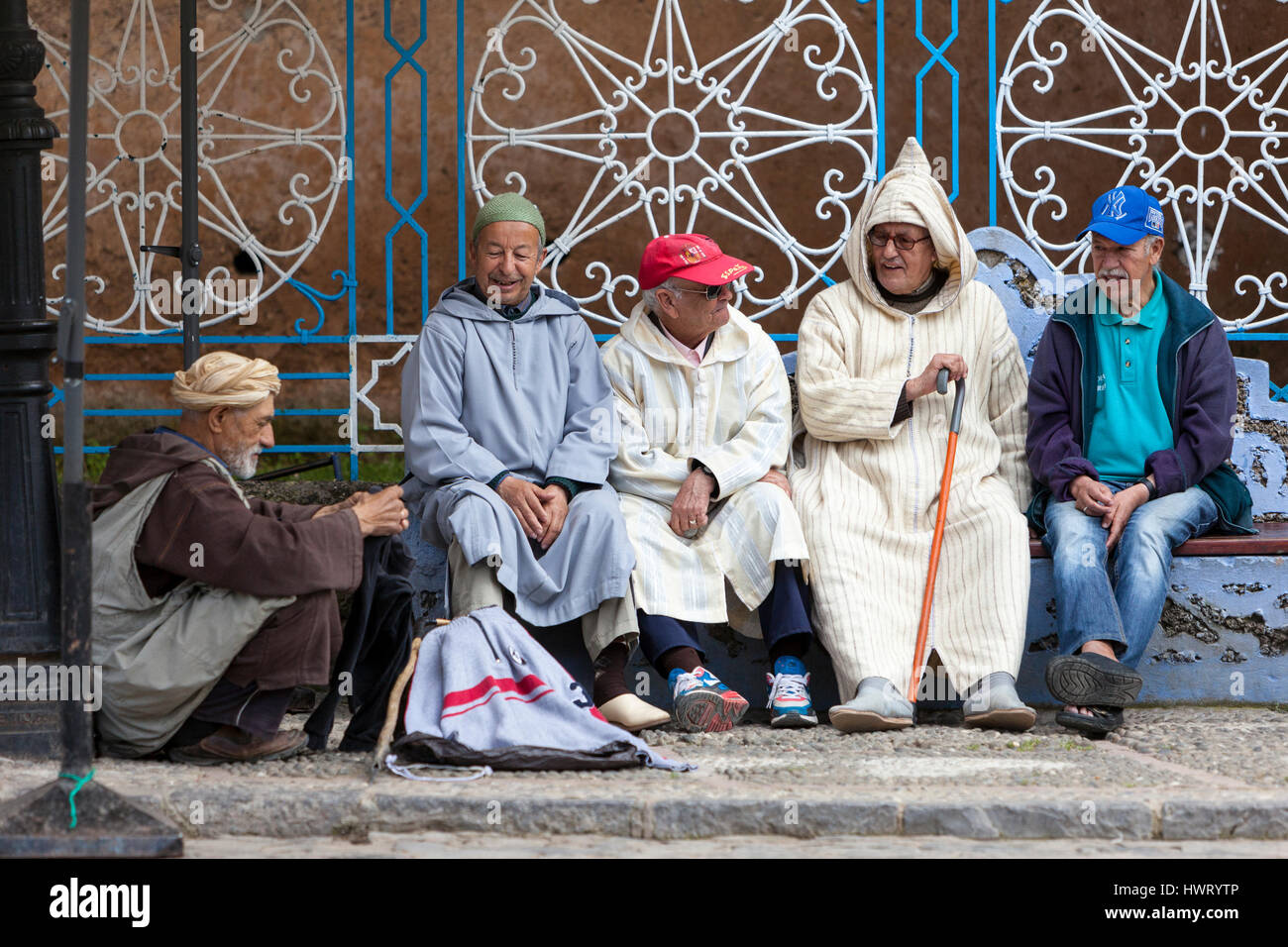 Chefchaouen, Maroc. Hommes parler sur la place publique, la démonstration d'une variété de styles de vêtements traditionnels et occidentaux. Banque D'Images