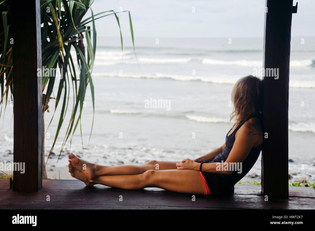 Vue latérale du woman looking at view tout en étant assis sur la plate-forme par beach Banque D'Images