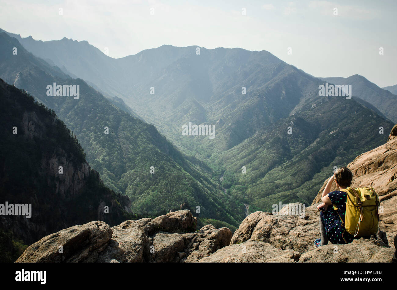 Vue arrière du randonneur assis sur des rochers contre montagne Banque D'Images