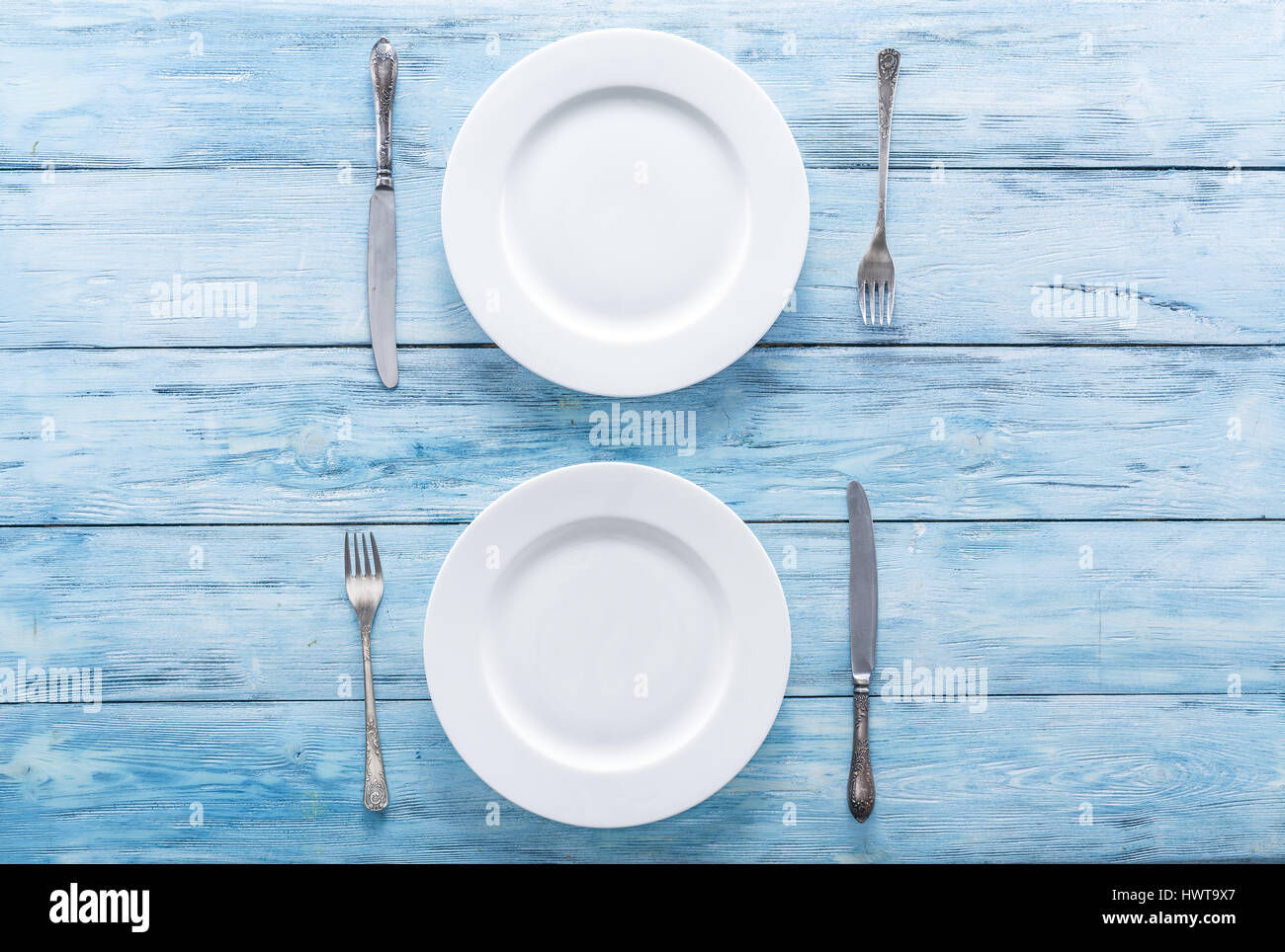 Deux assiettes et couverts vide blanc sur bleu table. Vue d'en haut. Banque D'Images