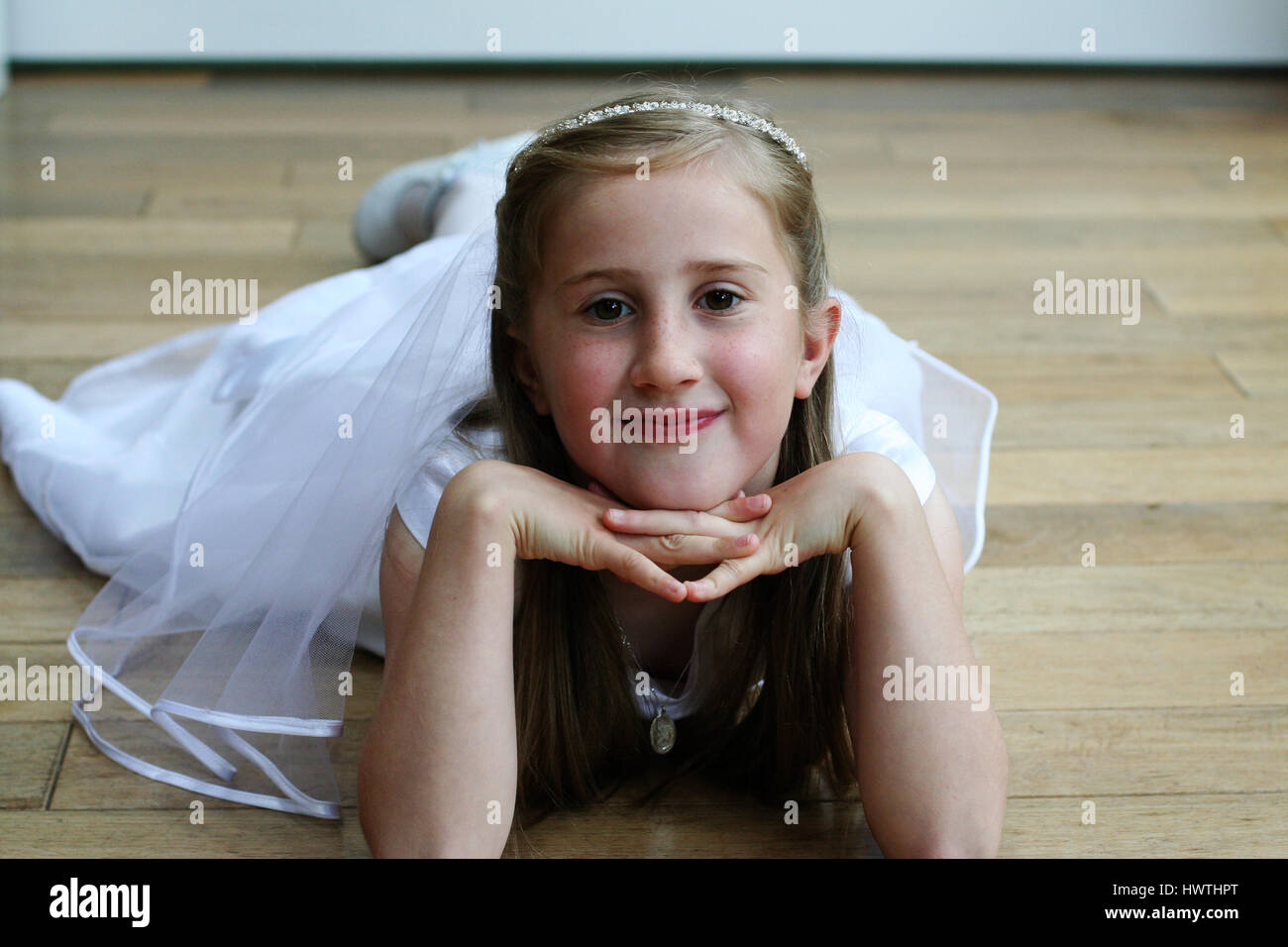 Première Communion fille couchée sur le ventre avec la tête appuyée par des mains Banque D'Images