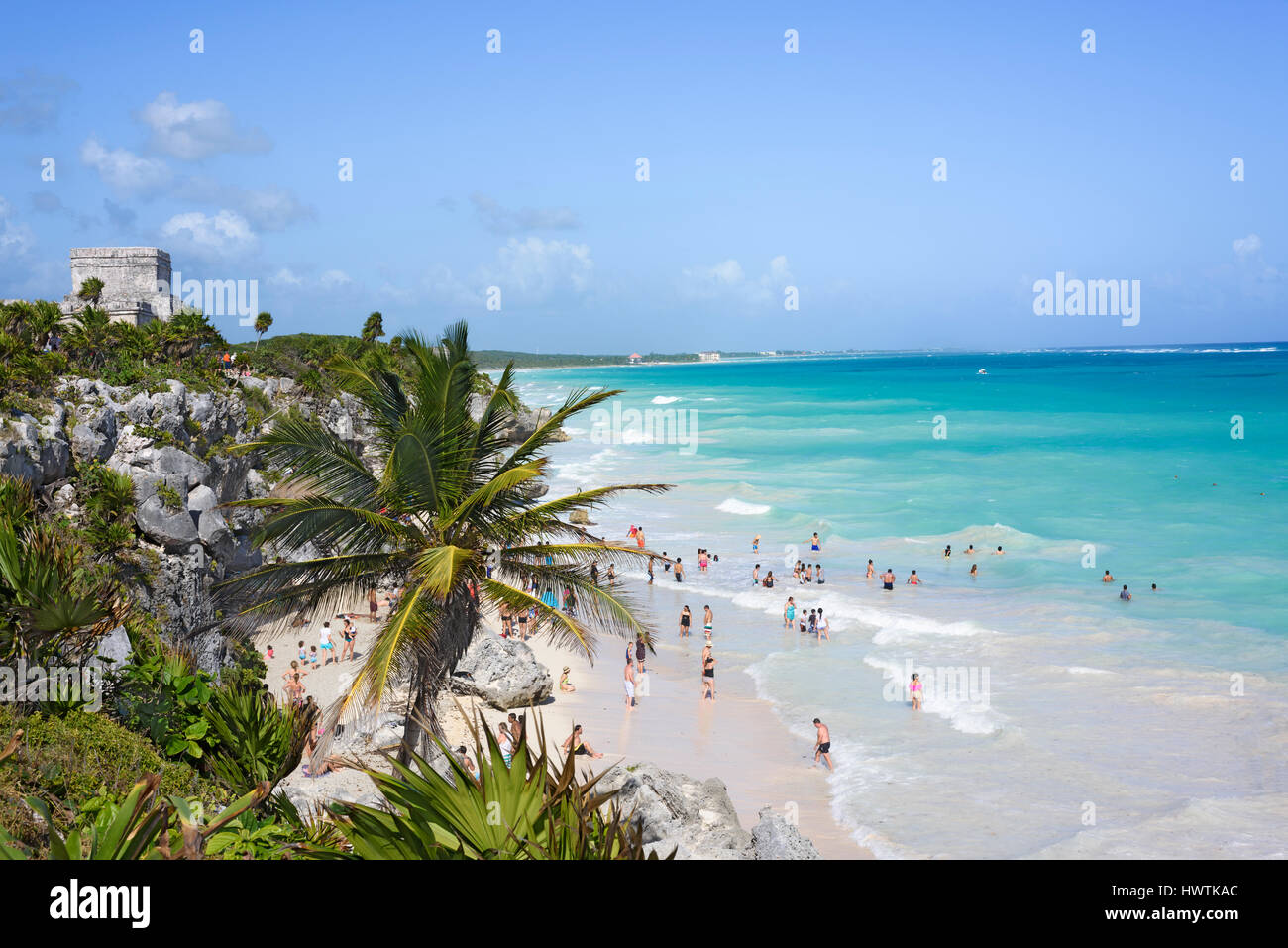 Vue de dessus de la mer des Caraïbes sous le ciel bleu, les gens s'amusant sur la plage de Tulum, Yucatan, Mexique, vert plante tropicale palmiers avant-plan Banque D'Images