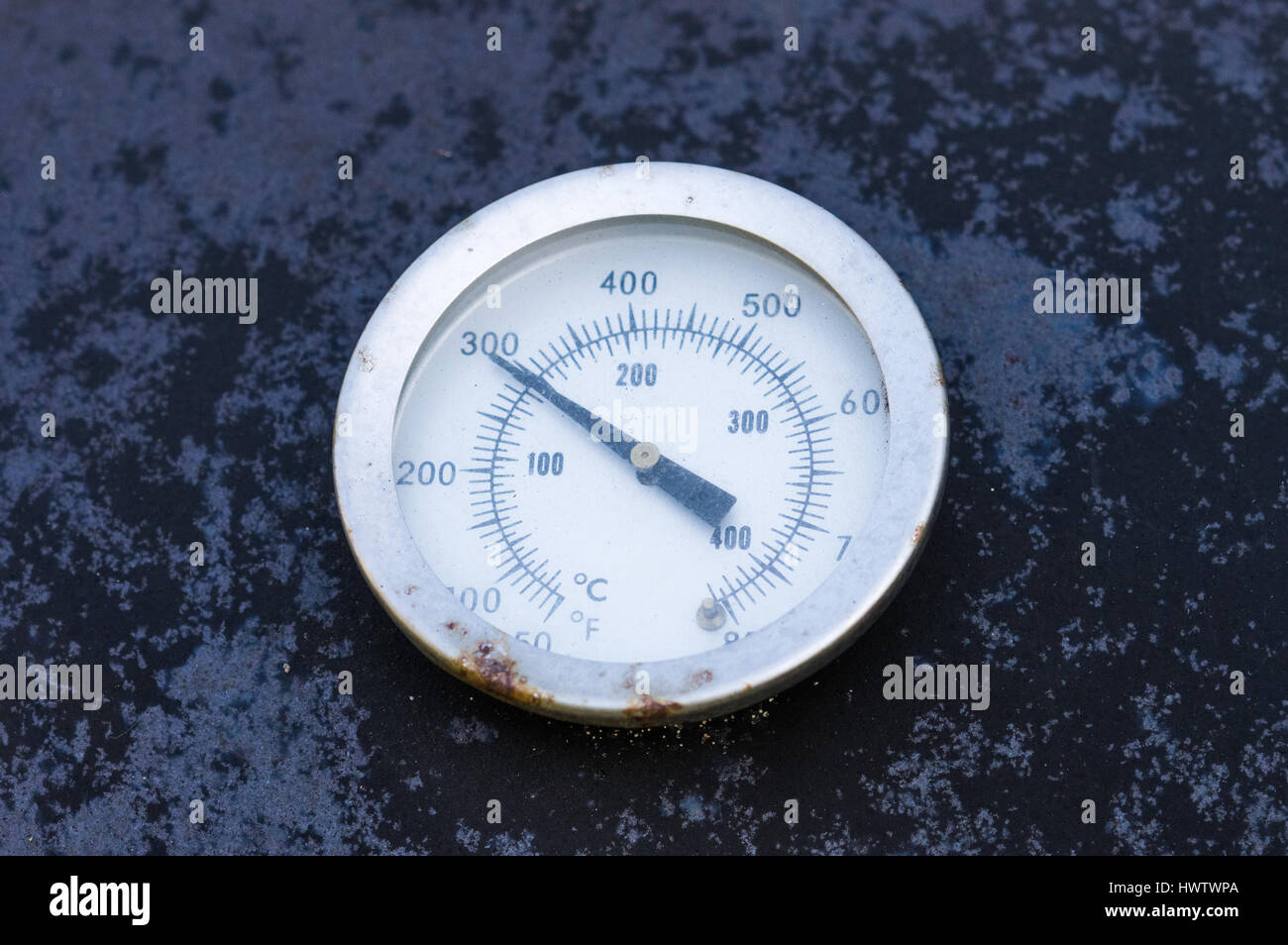 Gros plan d'un indicateur de température vieux rouillé sur un gril extérieur. Banque D'Images