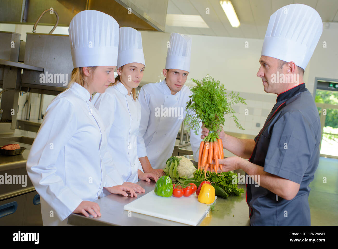 Chef holding bunch of carrots avant de stagiaires Banque D'Images