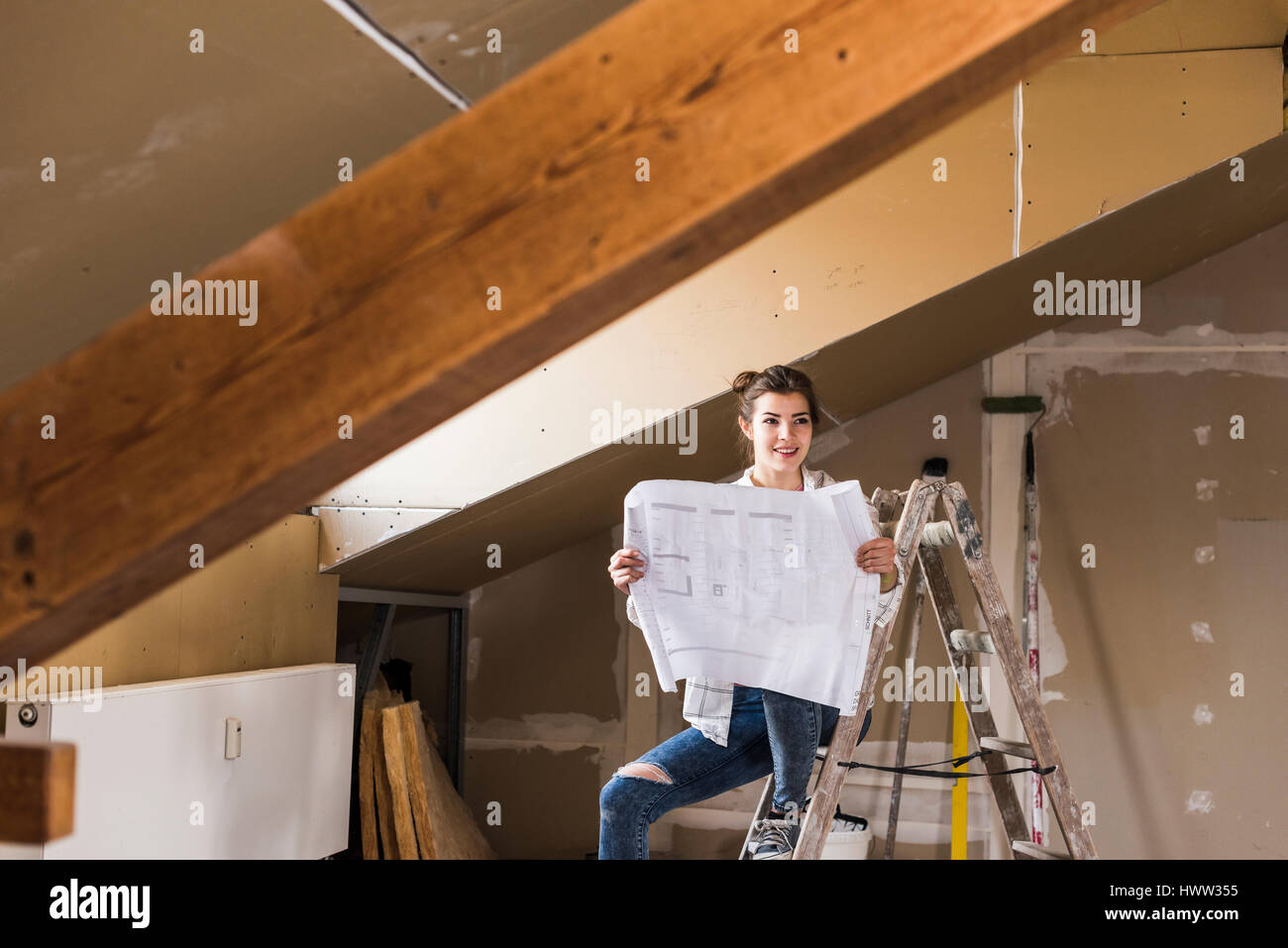 Jeune femme à la rénovation de sa nouvelle maison, holding construction plan Banque D'Images