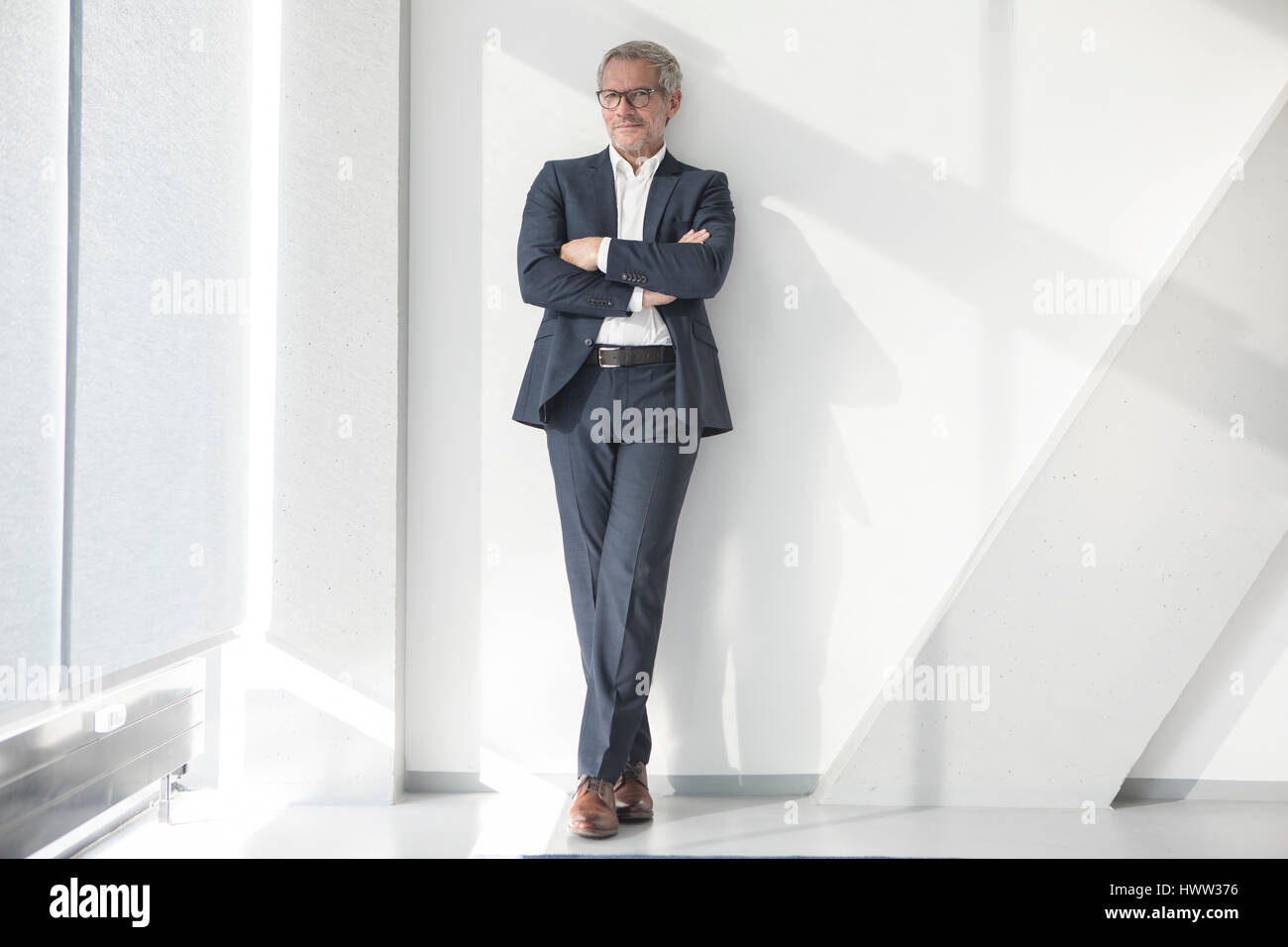 Confident businessman leaning against a wall Banque D'Images