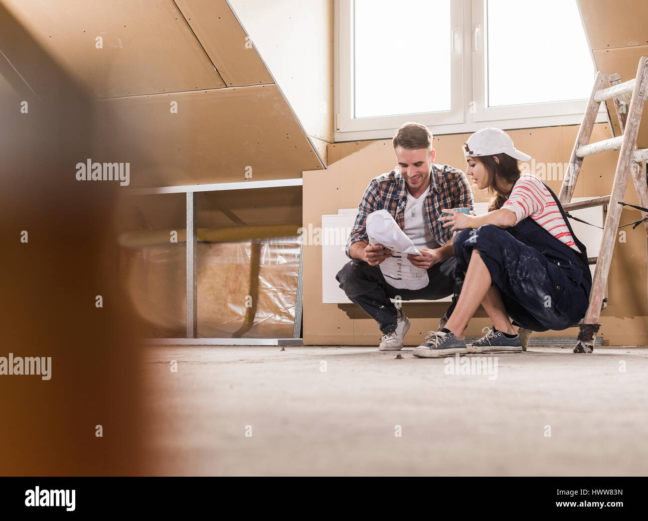 Jeune couple sur le site de construction de leur nouvelle maison, à la recherche de construction plan Banque D'Images