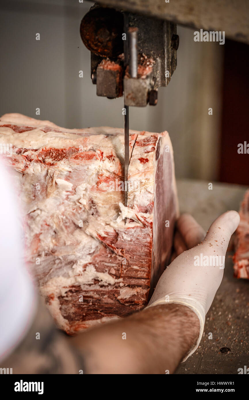 Butcher est couper la viande avec artiglio en boucherie Banque D'Images