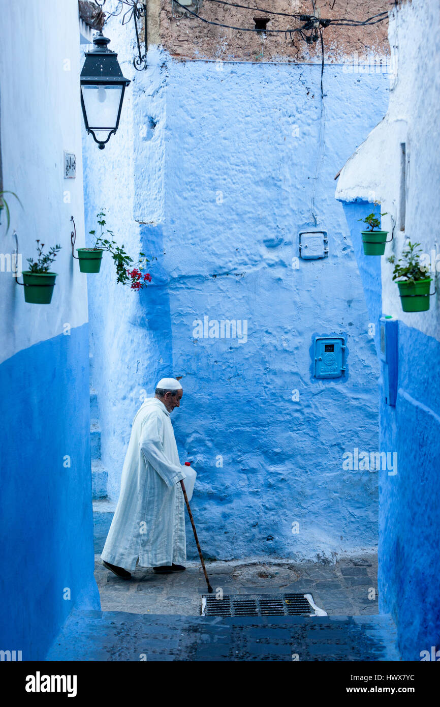 Chefchaouen, Maroc. Homme marchant avec une canne dans une rue étroite. Banque D'Images