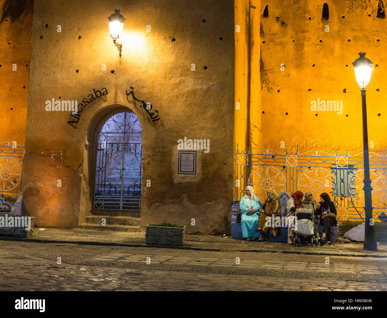 Chefchaouen, Maroc. Les femmes assises, parler à la place Outa El-Hammam, soir, par l'entrée de la Casbah, construite 1471. Banque D'Images
