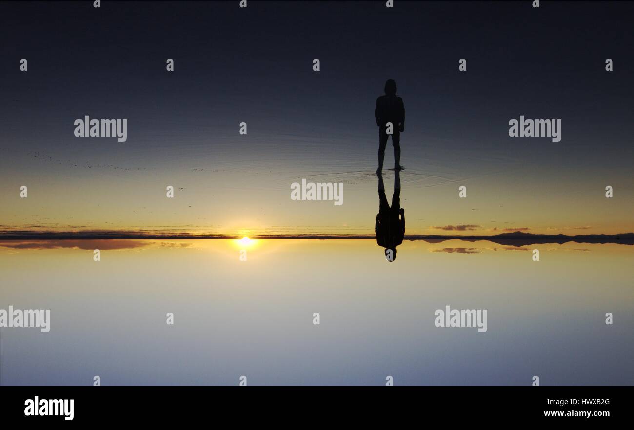 Rêve surréaliste d'un homme marchant dans télévision sel bolivien avec miroir fantastique. un coucher de soleil/ lever du soleil. à l'envers. Entre ciel et terre. lac calme. Banque D'Images