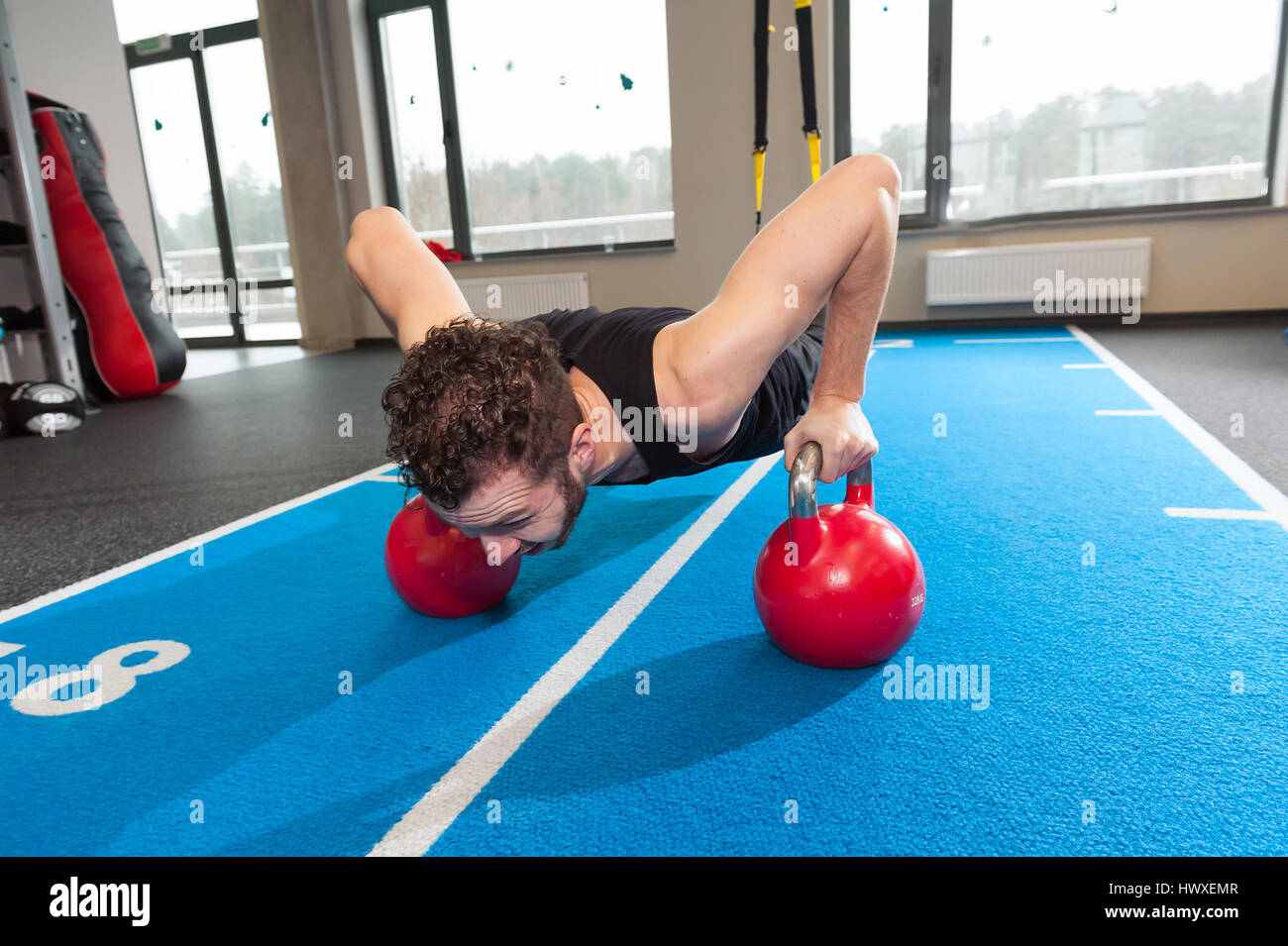 Barbu frisé blanc homme sportif de remise en forme de l'exercice avec un poids dans les sangles de barils de sport Banque D'Images