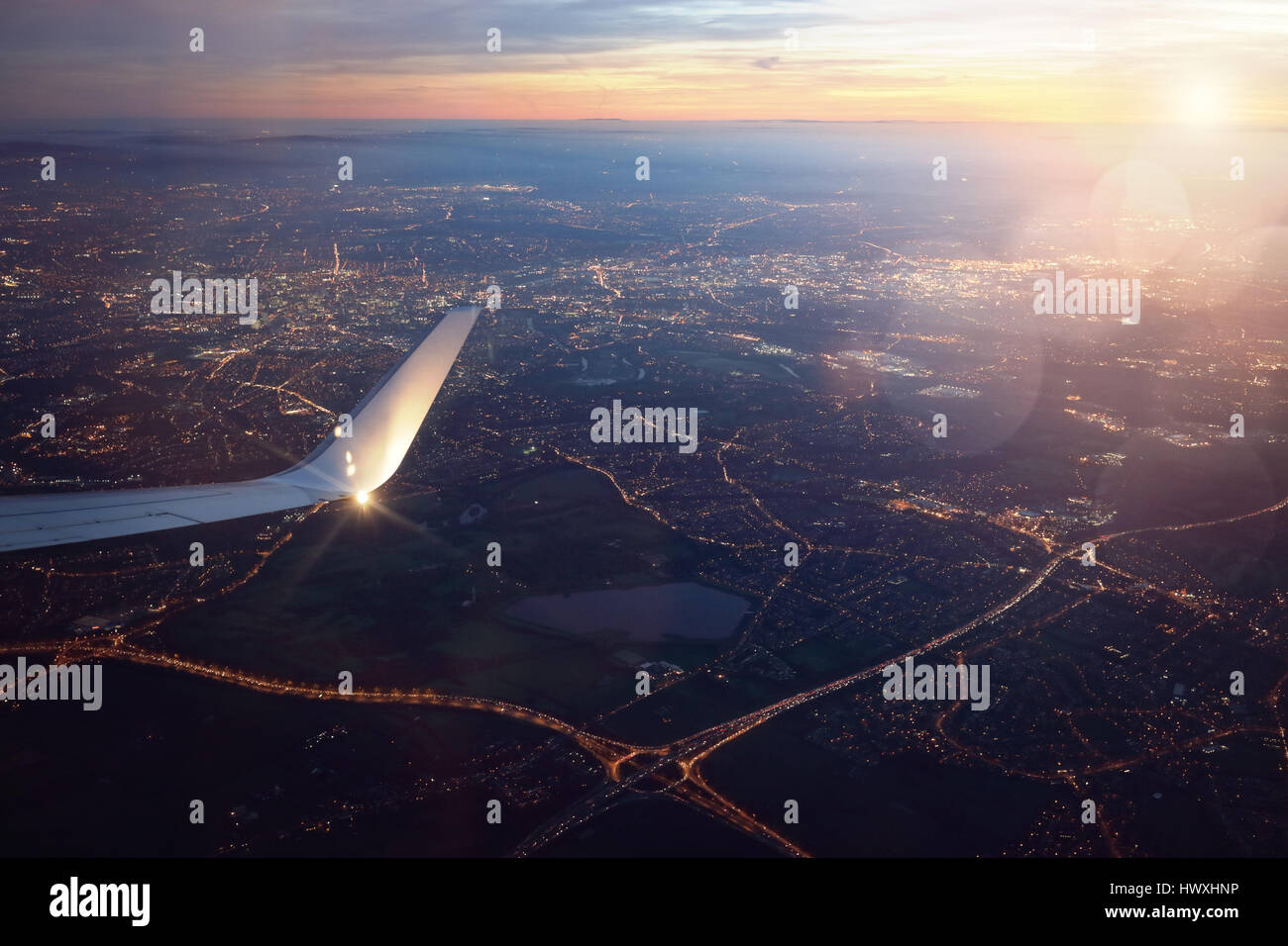 Vue depuis un avion à l'atterrissage par la fenêtre de la ville au coucher du soleil Banque D'Images