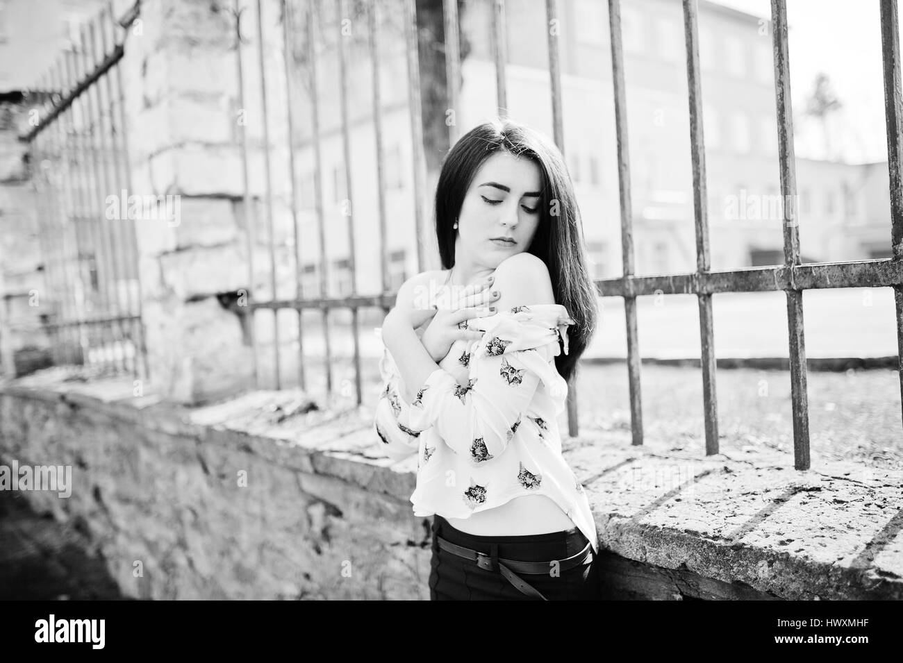 Jeune fille brune sur shirt élégant avec des chats et des pantalons bleu fond pose clôture de fer. Street Fashion model concept. Photo en noir et blanc. Banque D'Images