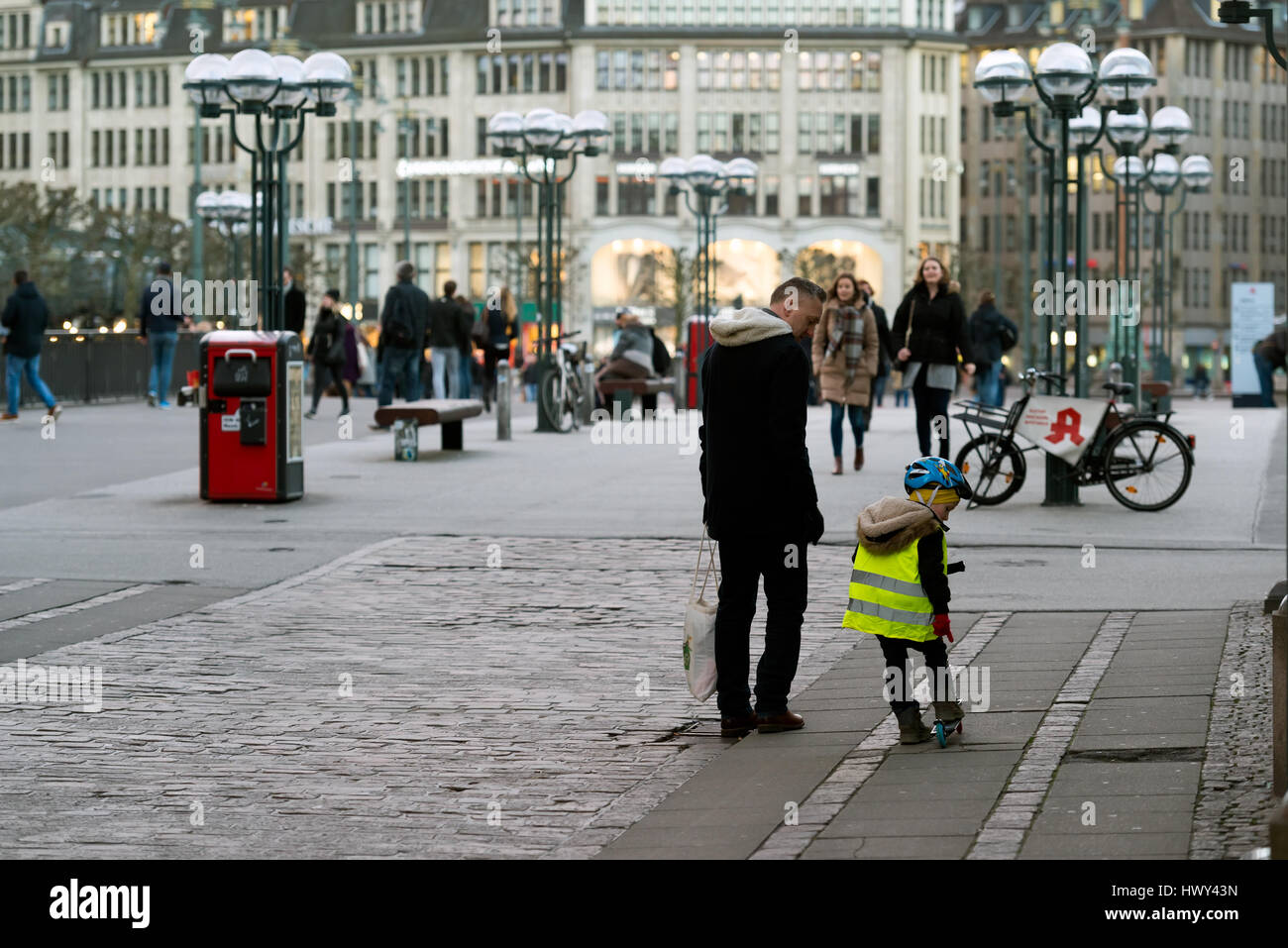 Hambourg, Allemagne - 10 mars 2017 : le père et le fils de marcher dans le centre de la ville, l'enfant sur un scooter wares une lumière réfléchie à l'ouest Banque D'Images Hambourg, Allemagne - 10 mars 2017 : le père et le fils de marcher dans le centre de la ville, l'enfant sur un scooter wares une lumière réfléchie à l'ouest Banque D'Images