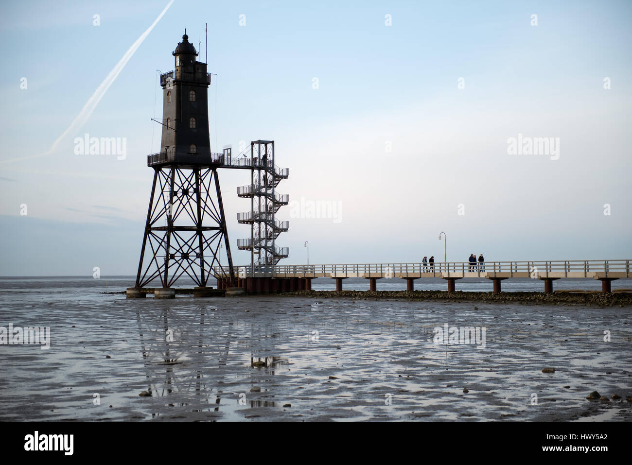 Bad Zwischenahn, Allemagne - 11 mars 2017 : les visiteurs de marcher le long de la Jetée du Phare au coucher du soleil en Obereversand pittoresque de la mer du Nord Banque D'Images Bad Zwischenahn, Allemagne - 11 mars 2017 : les visiteurs de marcher le long de la Jetée du Phare au coucher du soleil en Obereversand pittoresque de la mer du Nord Banque D'Images