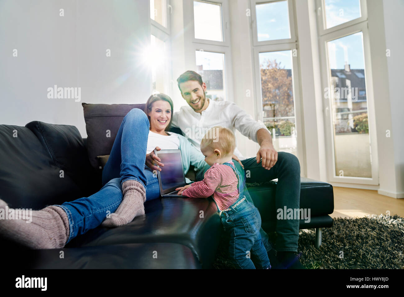 Les parents avec bébé girl using laptop on couch Banque D'Images