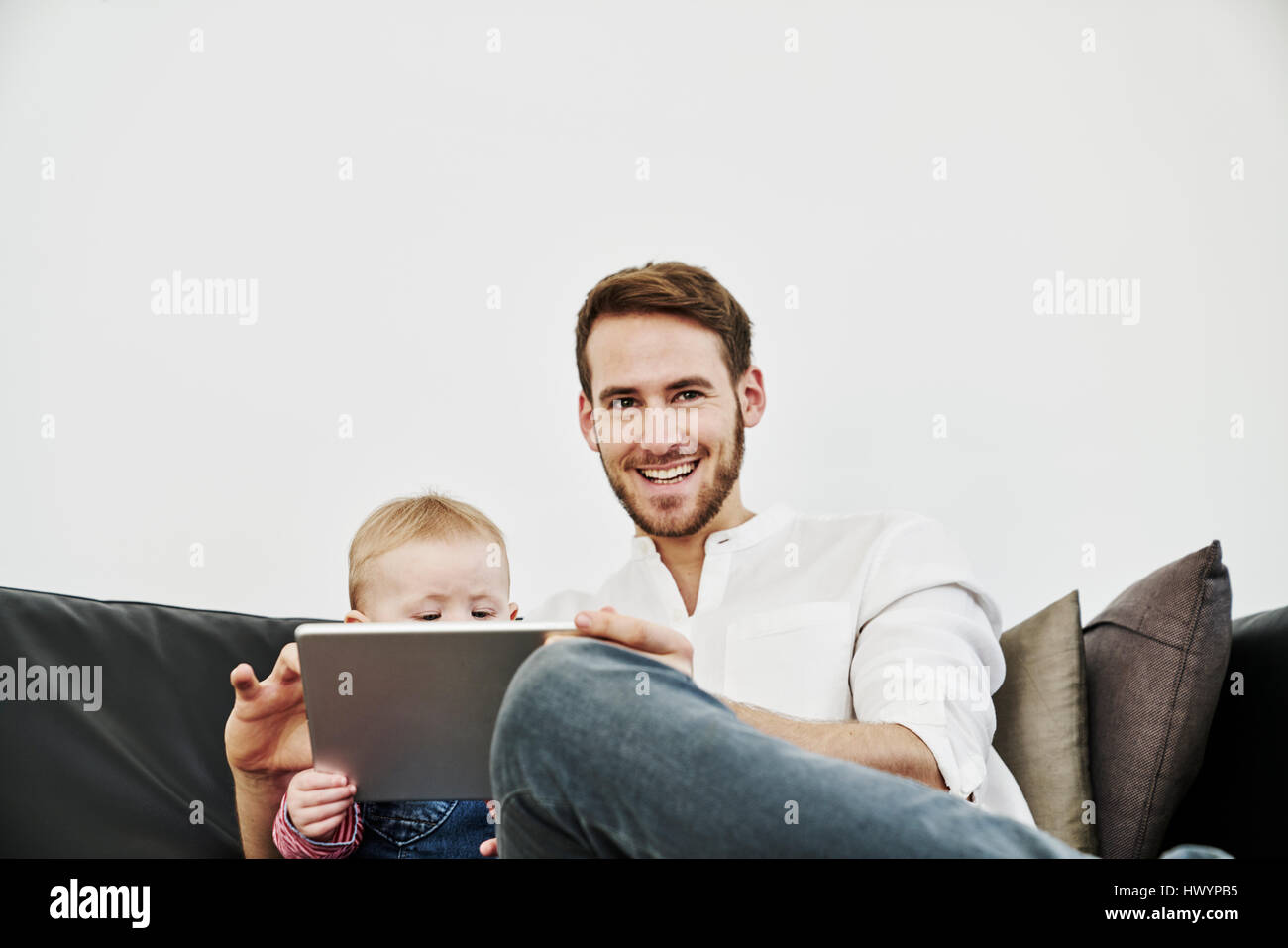 Père avec baby girl using tablet on couch Banque D'Images