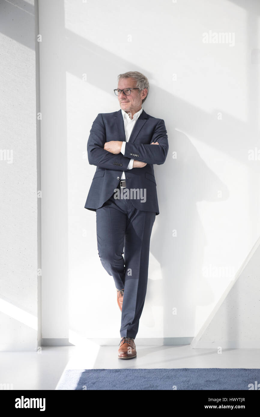 Confident businessman leaning against a wall Banque D'Images
