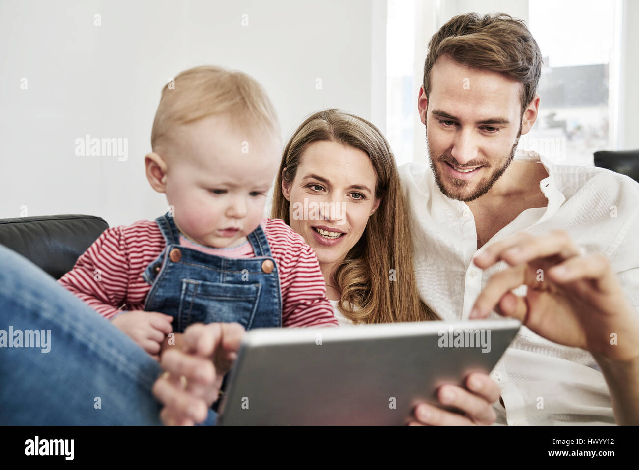 Parents with baby girl looking at tablet on couch Banque D'Images
