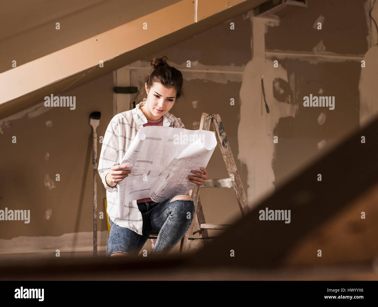 Jeune femme à la rénovation de sa nouvelle maison, holding construction plan Banque D'Images