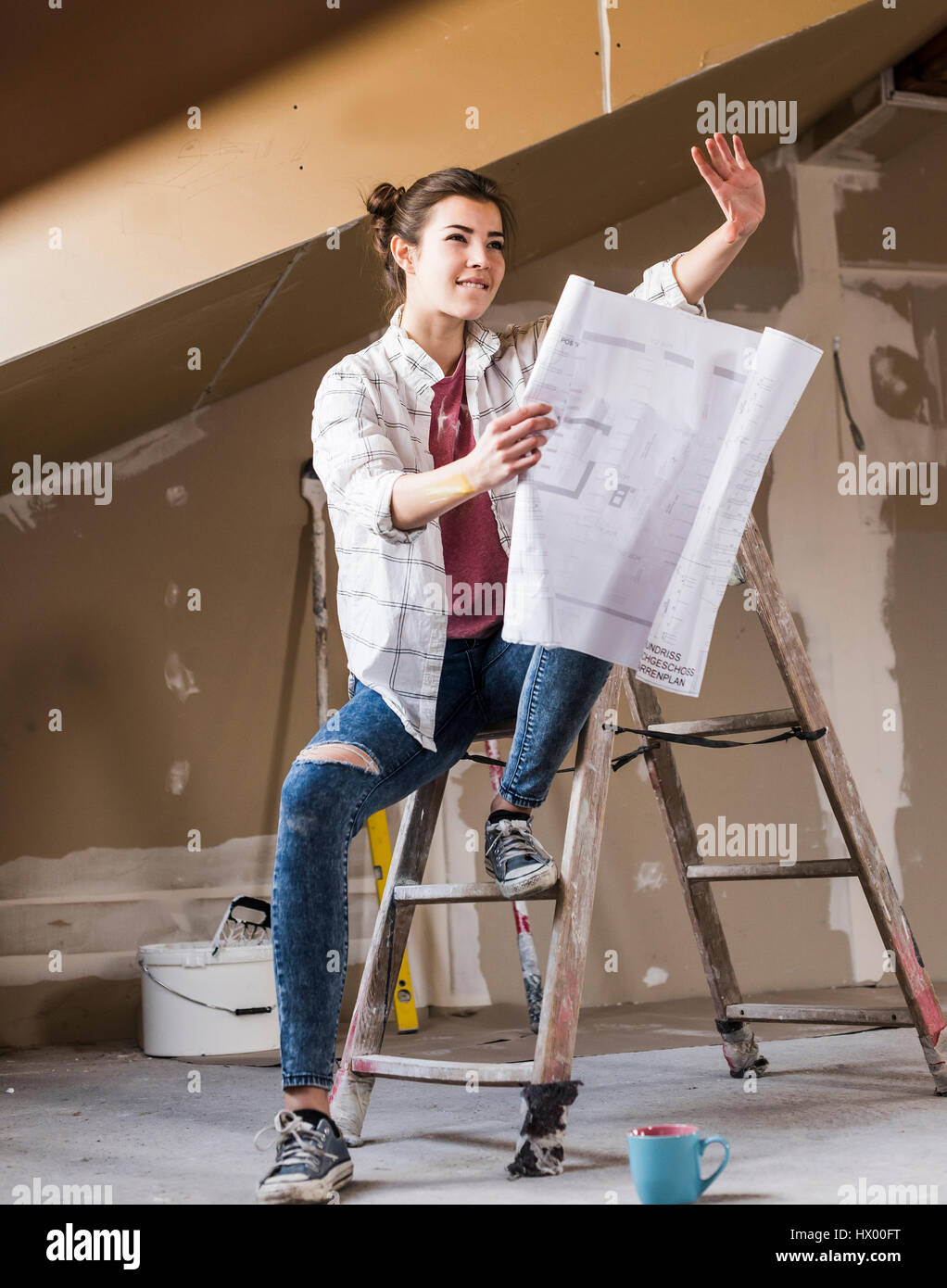 Jeune femme à la rénovation de sa nouvelle maison, holding construction plan Banque D'Images