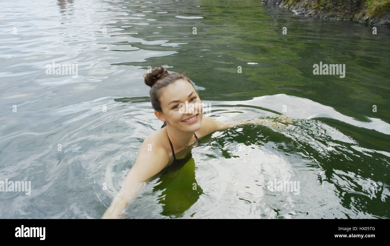 High angle portrait of smiling woman in bikini natation en piscine de l'eau à distance Banque D'Images