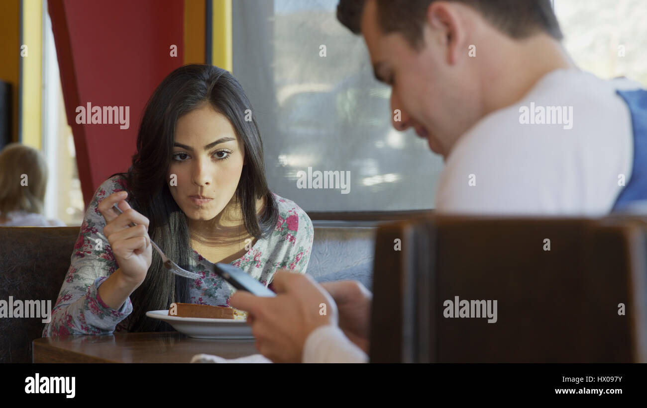 Selective focus vue avant de manger et de regarder la petite amie ami utiliser cell phone in restaurant Banque D'Images