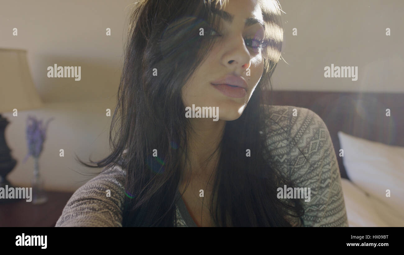 Close up portrait of sultry woman sitting on bed Banque D'Images