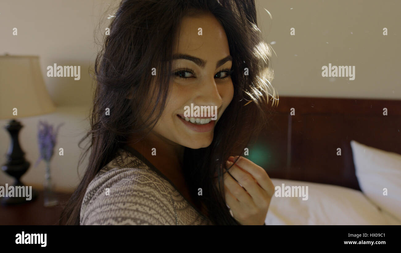 Close up portrait of smiling woman posing sitting on bed Banque D'Images