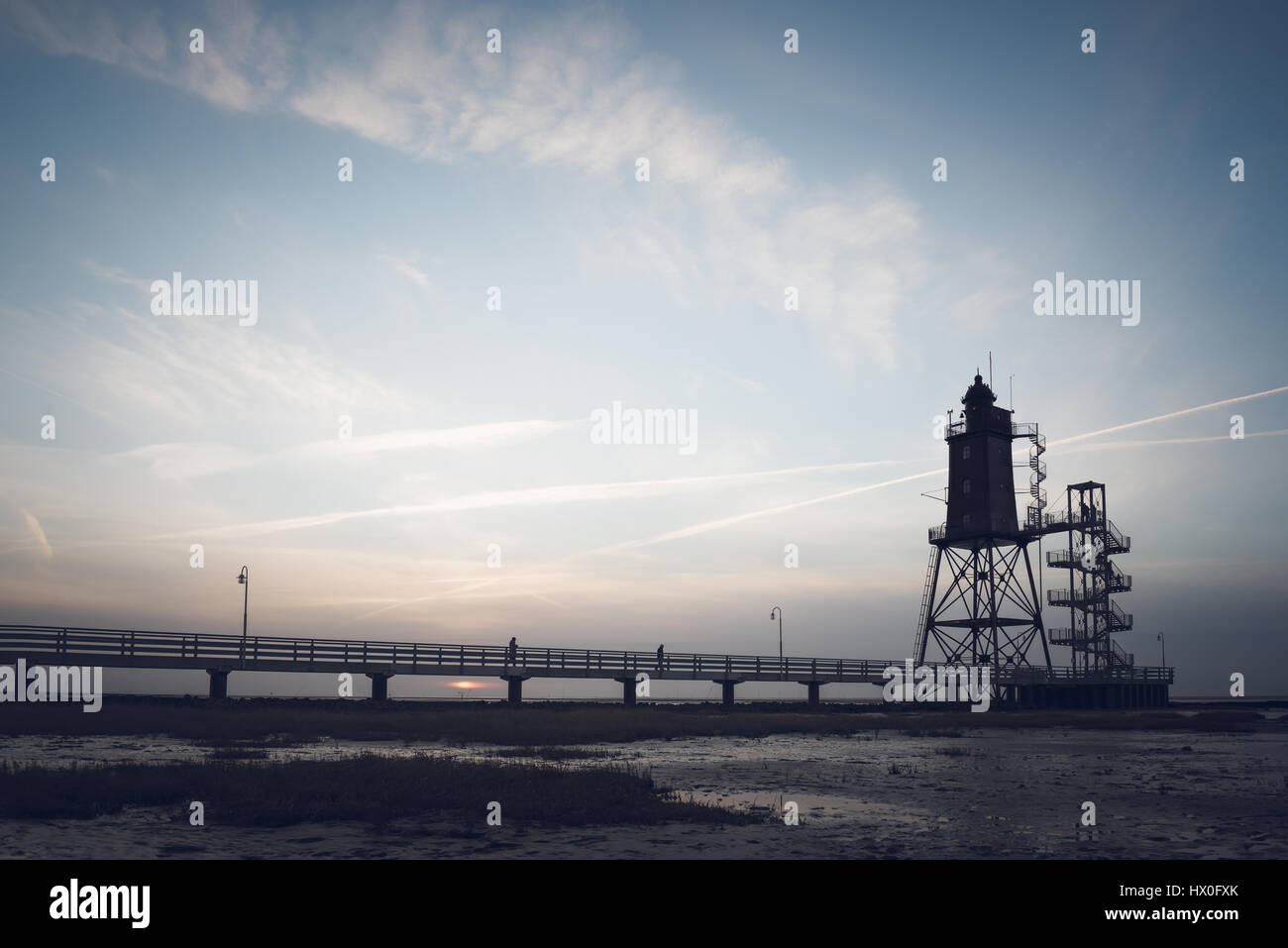 Bad Zwischenahn, Allemagne - 11 mars 2017 : les visiteurs de marcher le long de la Jetée du Phare au coucher du soleil en Obereversand pittoresque de la mer du Nord Banque D'Images Bad Zwischenahn, Allemagne - 11 mars 2017 : les visiteurs de marcher le long de la Jetée du Phare au coucher du soleil en Obereversand pittoresque de la mer du Nord Banque D'Images