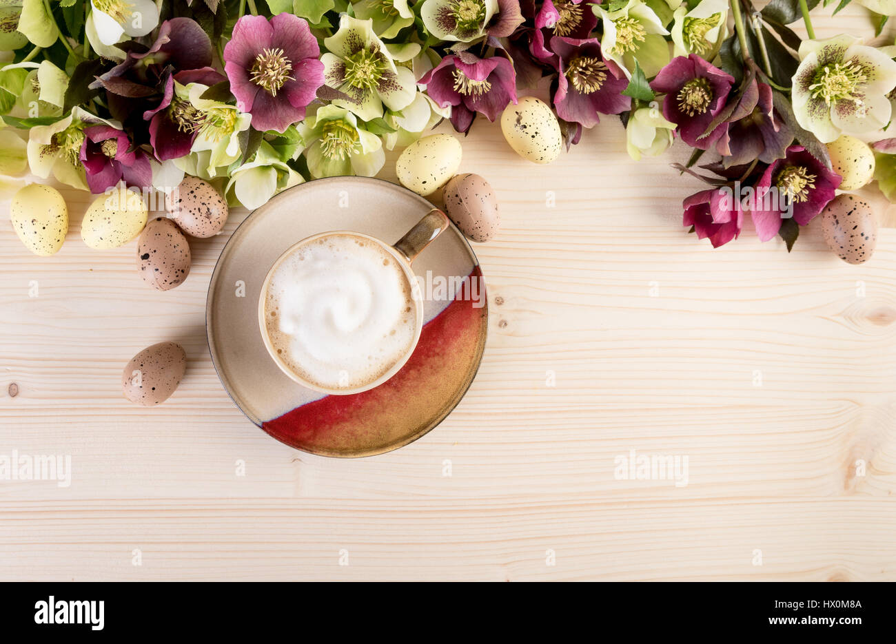 Tasse de café cappuccino avec fleurs de printemps et œuf de Pâques sur fond de bois clair. Vue de dessus, le texte de l'espace. Banque D'Images