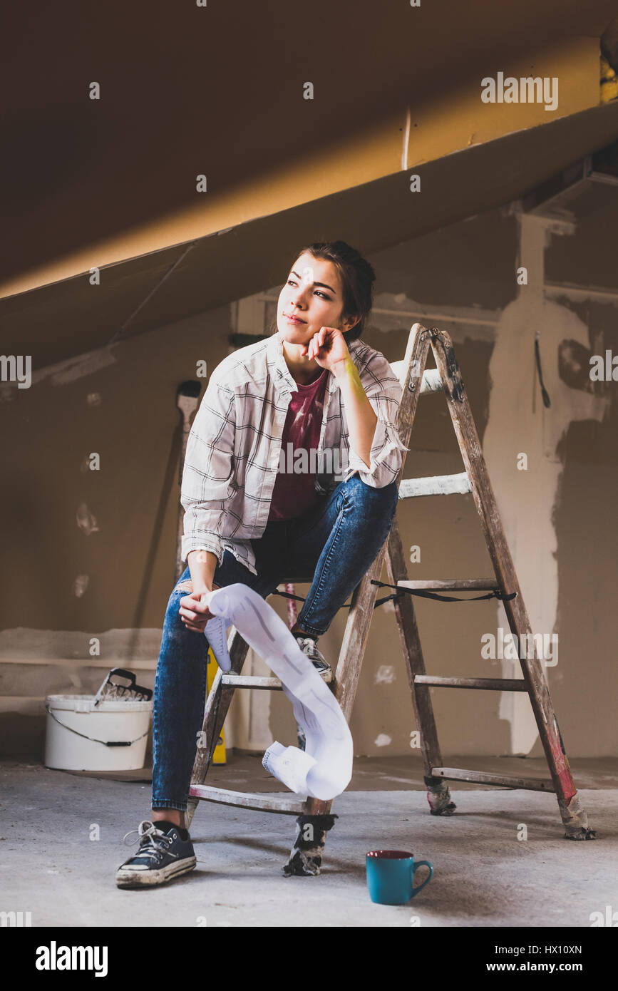 Jeune femme à la rénovation de sa nouvelle maison, holding construction plan Banque D'Images