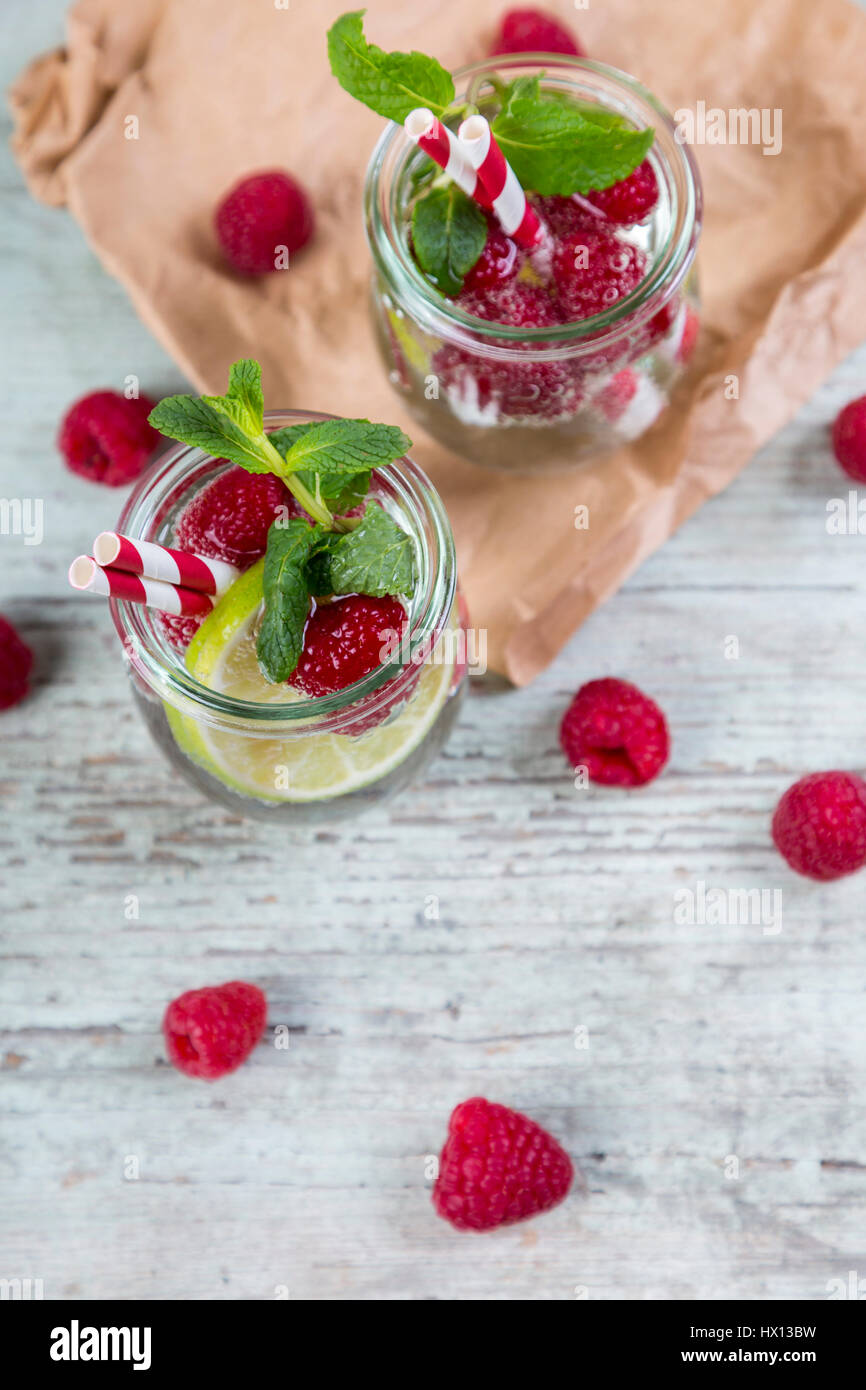 Verres d'eau avec limes et detox rasperries décoré de feuilles de menthe Banque D'Images