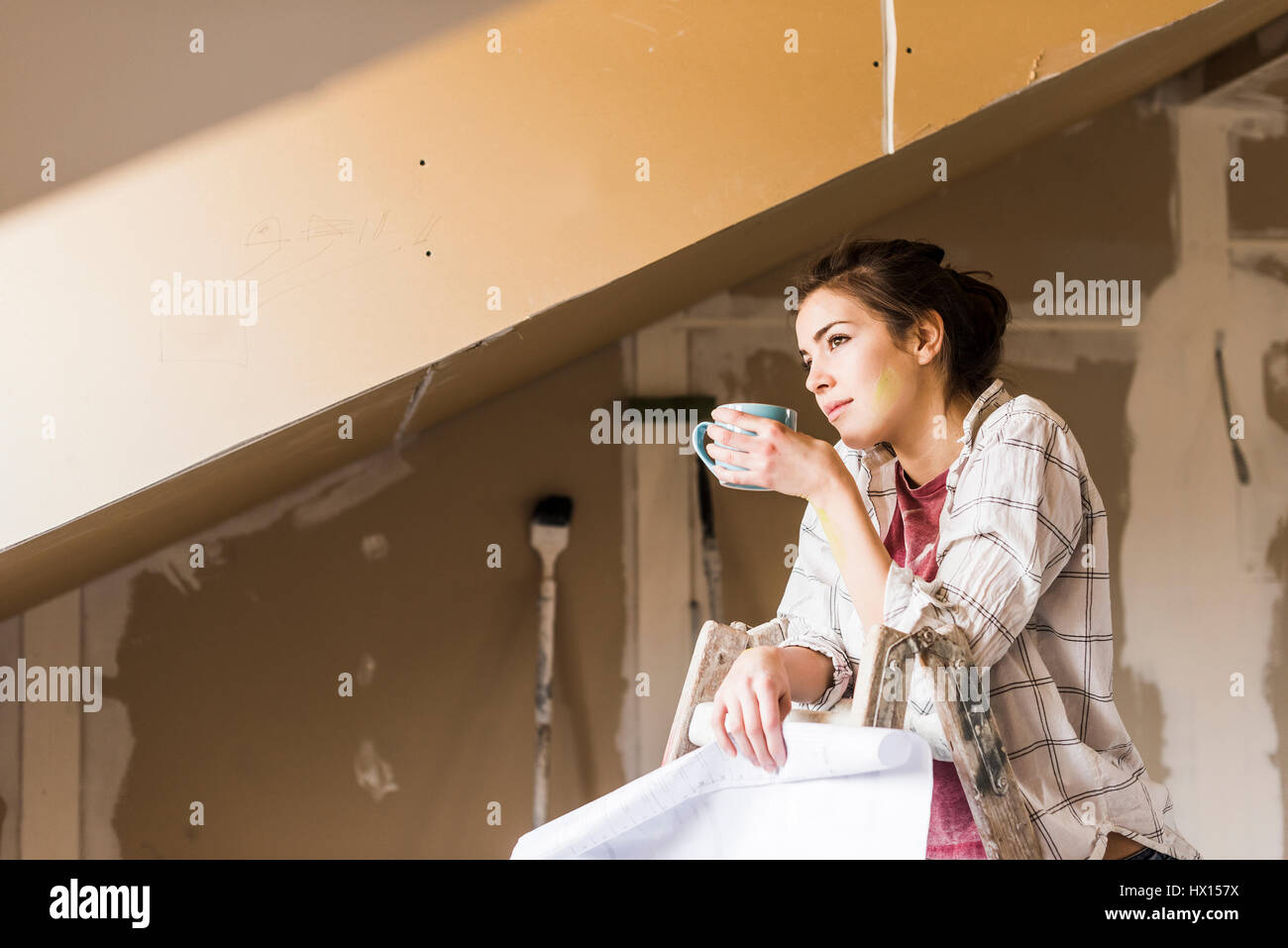 Jeune femme à la rénovation de sa nouvelle maison, holding construction plan Banque D'Images