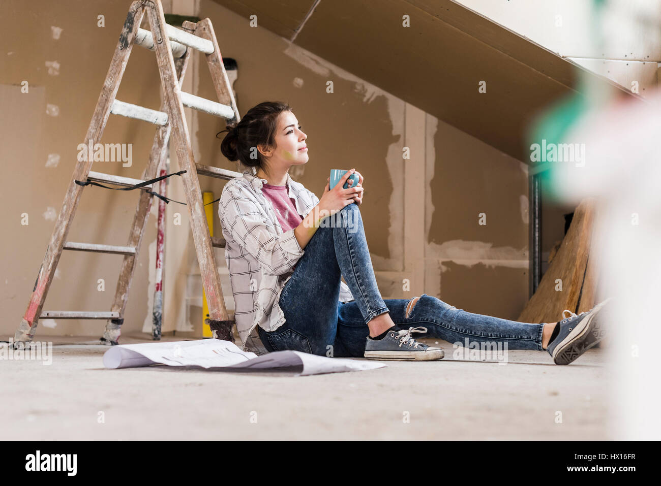 Jeune femme à la rénovation de sa nouvelle maison, holding construction plan Banque D'Images